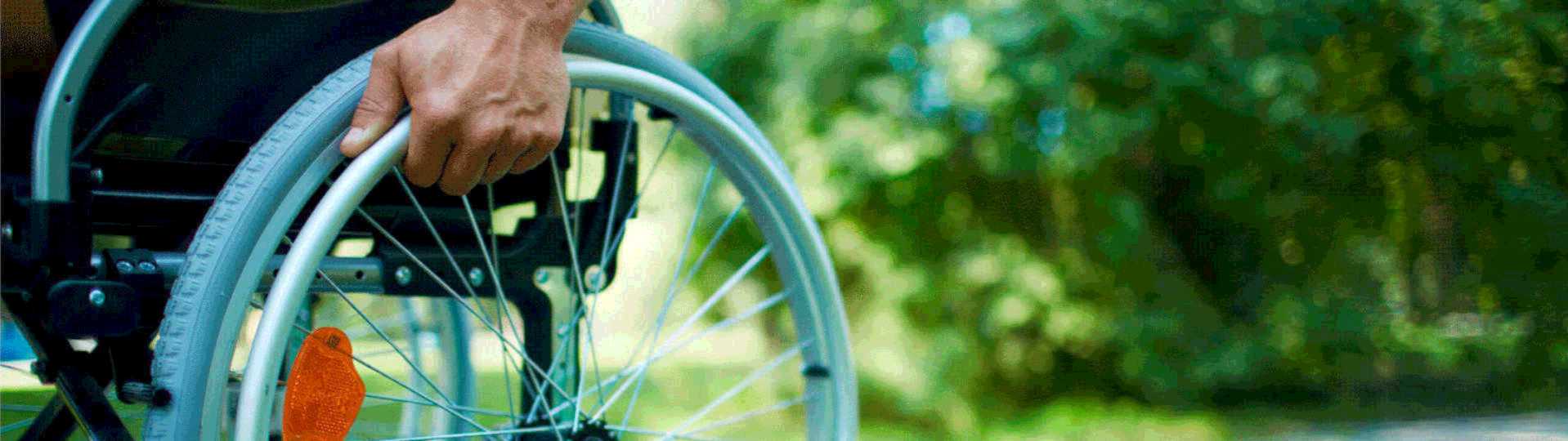 un primer plano de una persona en silla de ruedas, estÃ¡ empujando una rueda, el fondo de la imagen es de color verde